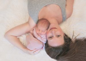 Mom with Newborn Baby Girl posed cuddling on flokati rug. Washngton DC Baby Photographer